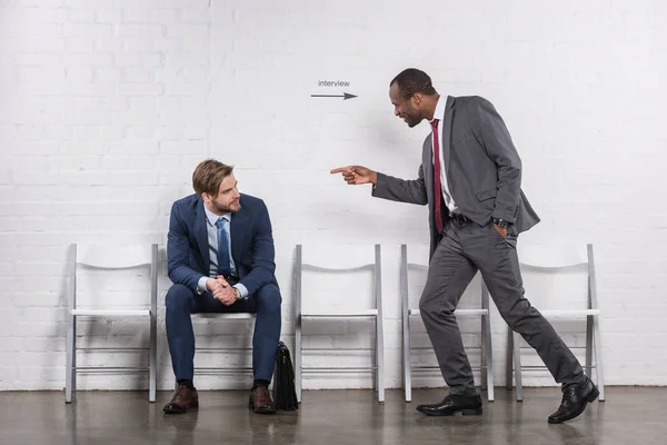 African american businessman pointing at caucasian colleague that waiting for job interview — Stock Photo