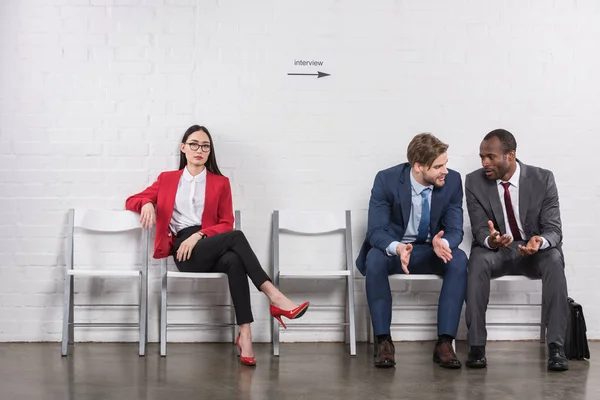 Multicultural businessmen having conversation near asian businesswoman while waiting for job interview — Stock Photo