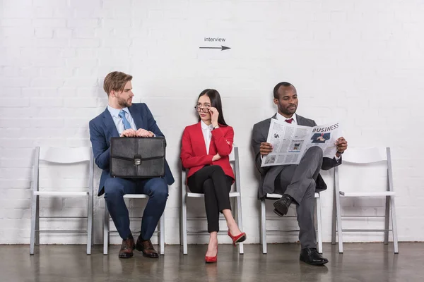 Multiethnische Geschäftsleute sitzen auf Stühlen und warten auf ein Vorstellungsgespräch — Stockfoto