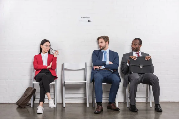 Multiethnische Geschäftsleute schauen einander beim Warten auf ein Vorstellungsgespräch an — Stockfoto