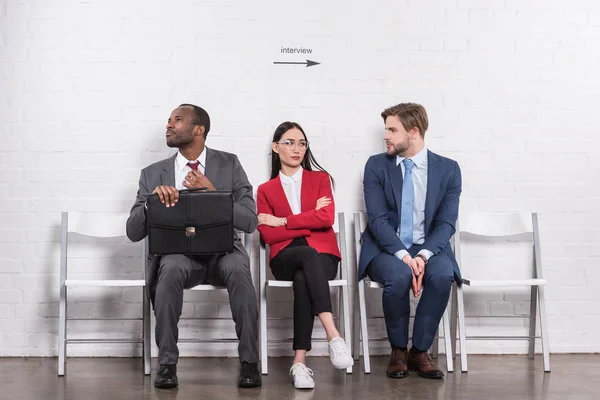 Multiethnische Geschäftsleute sitzen auf Stühlen und warten auf ein Vorstellungsgespräch — Stockfoto