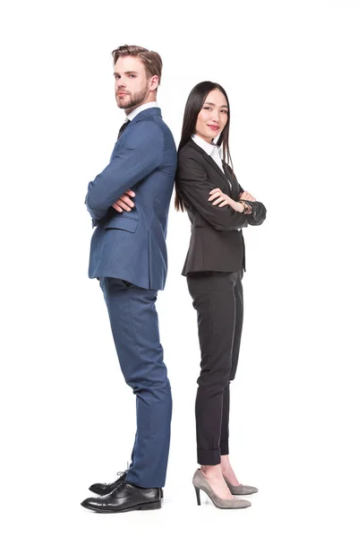 Vista lateral de colegas de negocios multiculturales con los brazos cruzados parados espalda con espalda aislados en blanco - foto de stock