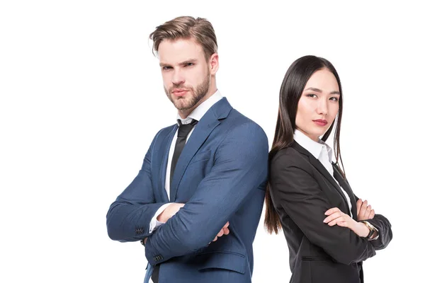 Side view of multicultural business colleagues with arms crossed standing back to back isolated on white — Stock Photo