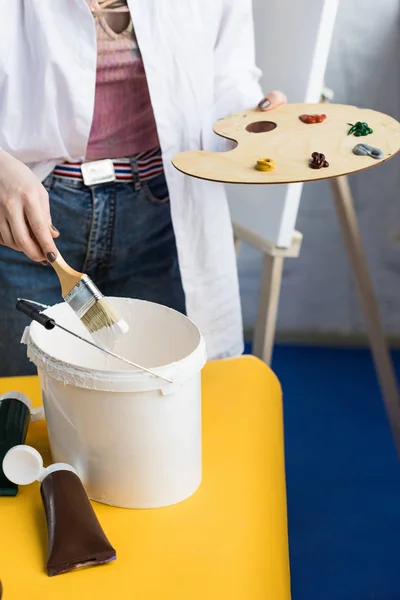 Young creative girl mixing paint in light studio — Stock Photo