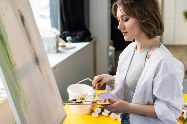 Young inspired girl mixing paint in light studio — Stock Photo