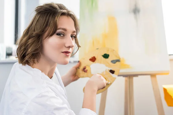 Young artistic girl mixing paint in light studio — Stock Photo