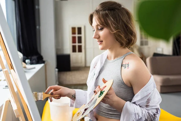 Jeune fille créative peinture sur toile en studio de lumière — Photo de stock