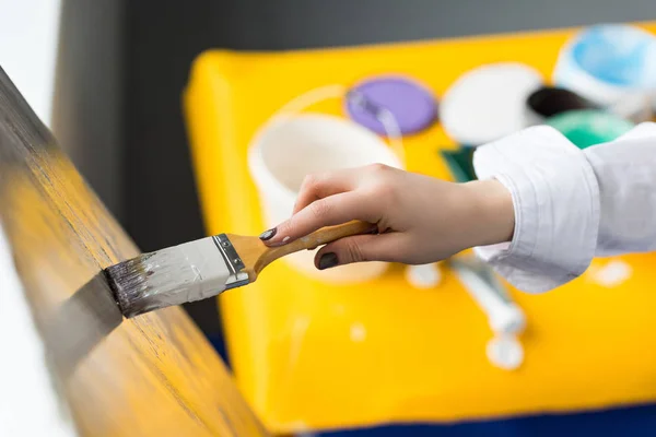 Young artistic girl painting on canvas in light studio — Stock Photo