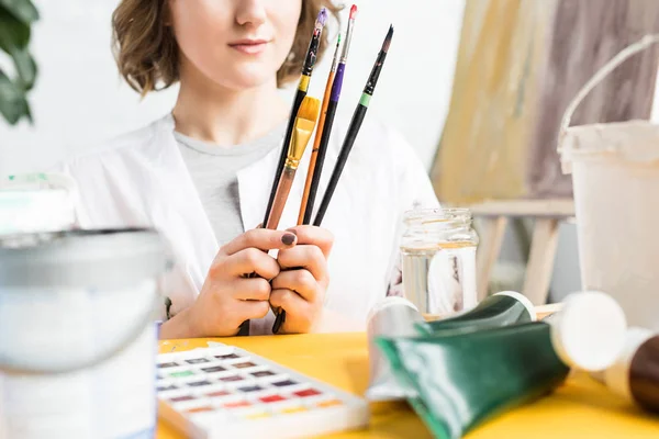 Close-up view of young artistic girl with brushes in hands in light studio — Stock Photo