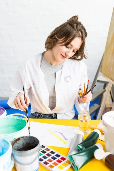 Молода художня дівчина робить зразки фарби в легкій студії — стокове фото