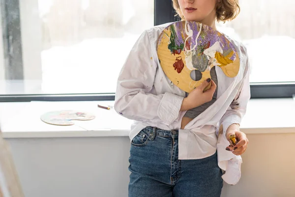 Молода натхненна дівчина тримає палітру в легкій студії — стокове фото