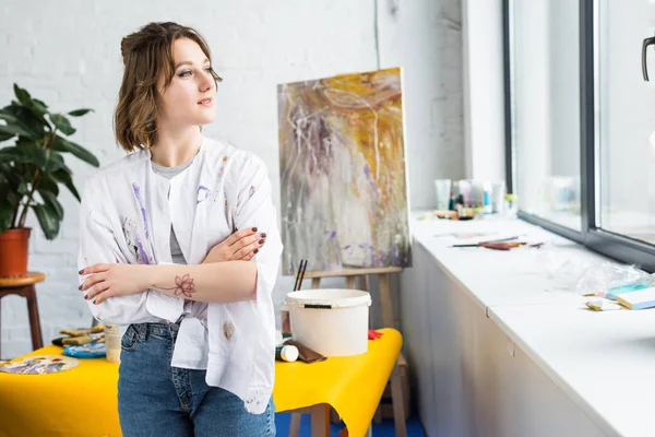 Young artistic girl looking in window in light studio — Stock Photo