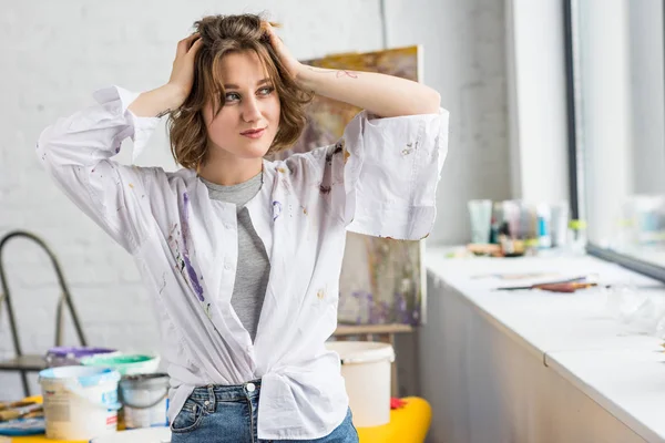 Joven chica inspirada de pie con las manos en la cabeza en el estudio de luz - foto de stock