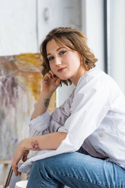 Young creative girl sitting on windowsill in light studio — Stock Photo