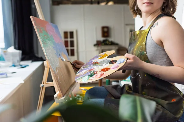 Vue rapprochée d'une jeune fille inspirée peignant en studio de lumière — Photo de stock