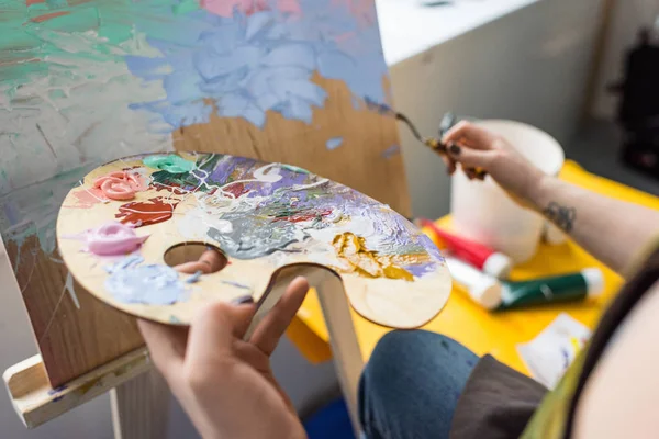 Close-up view of girl with palette in hands in light studio — Stock Photo