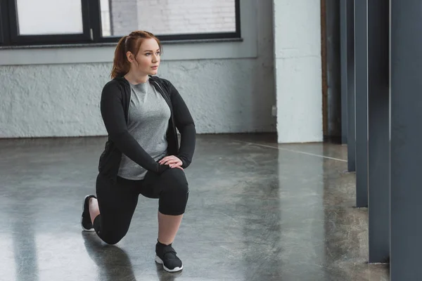 Ожирение девушка выполняет упражнения на растяжку в тренажерном зале — стоковое фото