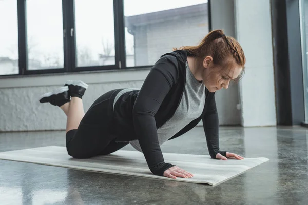 Chica con sobrepeso haciendo flexiones en el gimnasio - foto de stock