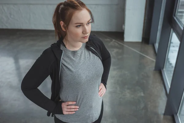 Избыточный вес определяется девушка стоя в тренажерном зале — стоковое фото