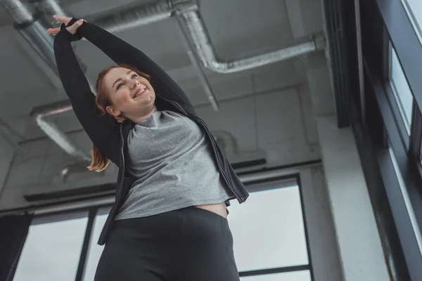 Kurvige Mädchen in der Turnhalle strecken ihre Arme — Stockfoto