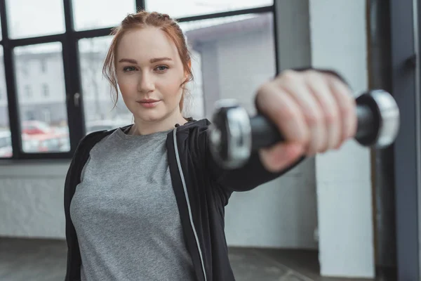 Overweight girl lifting dumbbell in gym — Stock Photo
