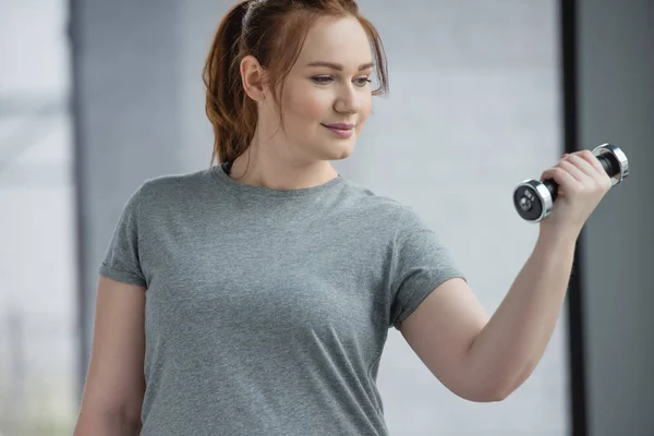 Curvy girl training with dumbbell in gym — Stock Photo