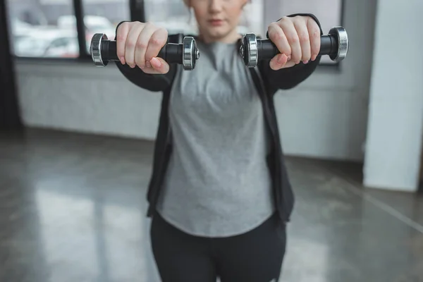 Chica obesa haciendo ejercicio con pesas en el gimnasio - foto de stock