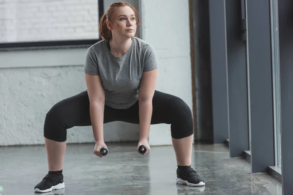 Chica curvilínea levantando pesas en el gimnasio - foto de stock