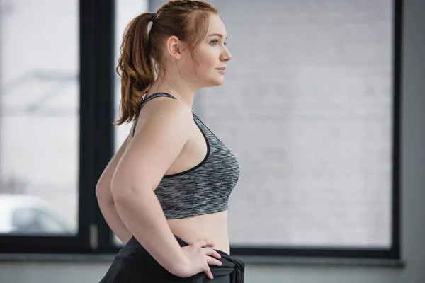 Curvy girl wearing sports top in sports center — Stock Photo