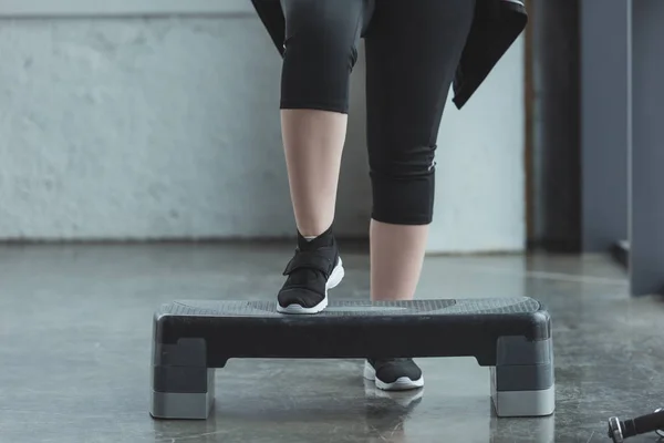 Curvy menina se exercitando na plataforma passo no ginásio — Fotografia de Stock