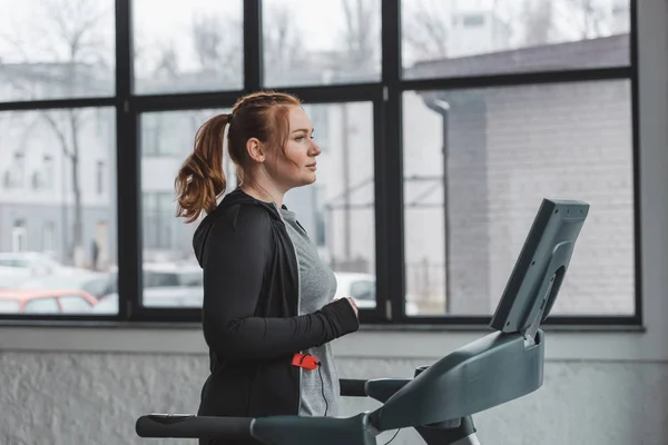 Overweight girl running on treadmill in sports center — Stock Photo