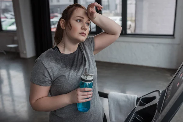 Chica curvas con botella de agua en la cinta de correr en el gimnasio - foto de stock