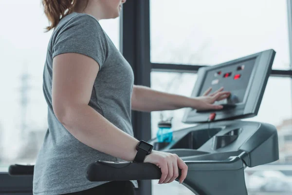 Curvy girl adjusting treadmill in gym — Stock Photo