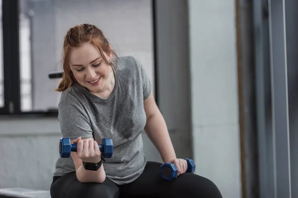 Curvy girl training with dumbbells in gym — Stock Photo