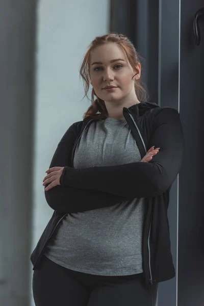 Толстая девушка, стоящая у окна в спортзале — стоковое фото