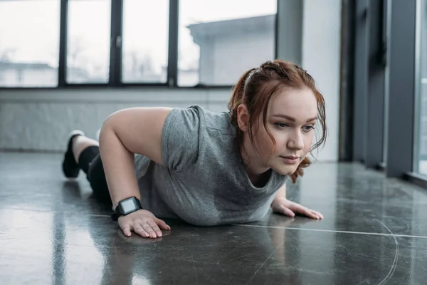 Ragazza obesa che esegue flessioni in palestra — Foto stock