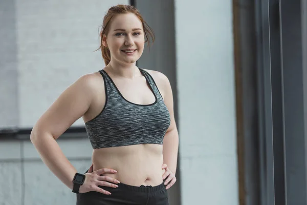 Curvy girl standing by window in gym — Stock Photo