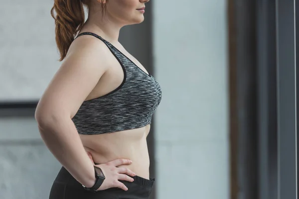 Крупним планом вид на дівчину з ожирінням, що стоїть біля вікна в спортзалі — стокове фото