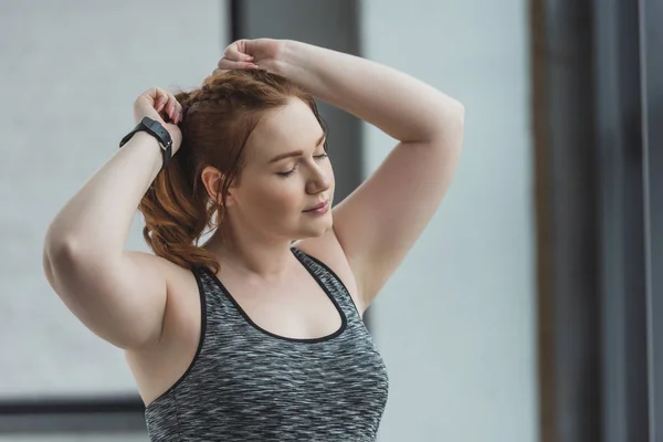 Obese girl fixing her hair in gym — Stock Photo