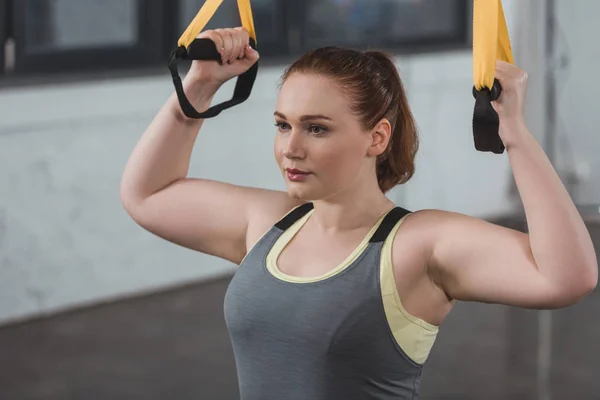 Curvas de entrenamiento de chica en correas de suspensión en el gimnasio - foto de stock