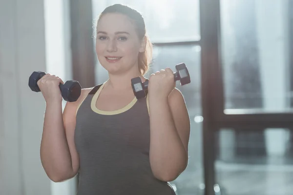 Addestramento femminile in sovrappeso con manubri in palestra — Foto stock