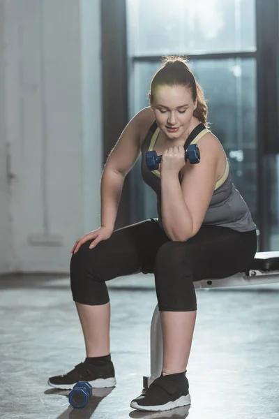 Overweight girl training with dumbbell in gym — Stock Photo