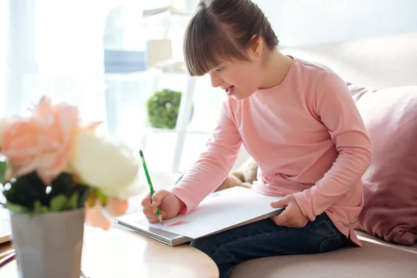 Niedliches Kind mit Down-Syndrom zeichnet mit Bleistift — Stockfoto