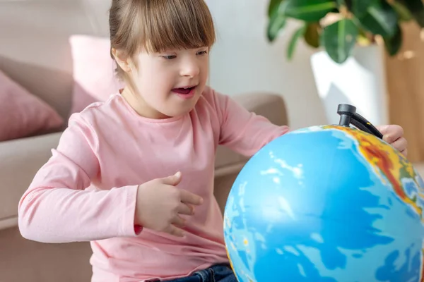 Child with down syndrome looking at globe — Stock Photo