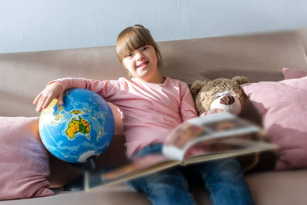 Niño con síndrome de Down leyendo libro y jugando con globo - foto de stock