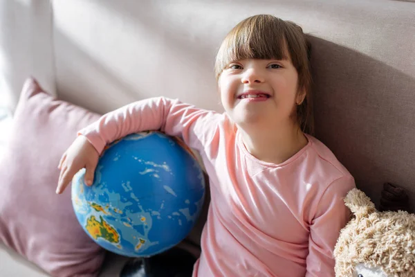 Smiling child with down syndrome holding globe — Stock Photo