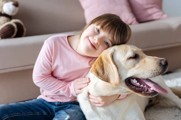 Niño con síndrome de Down abrazándose con el perro - foto de stock