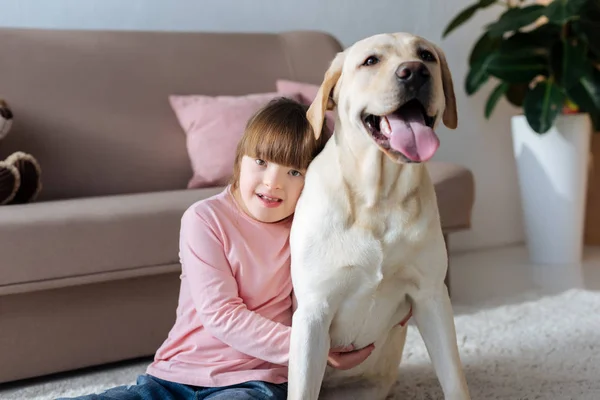 Criança com síndrome de down abraçando Labrador retriever — Fotografia de Stock