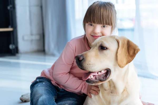 Kid with down syndrome and Labrador retriever resting on the floor — Stock Photo
