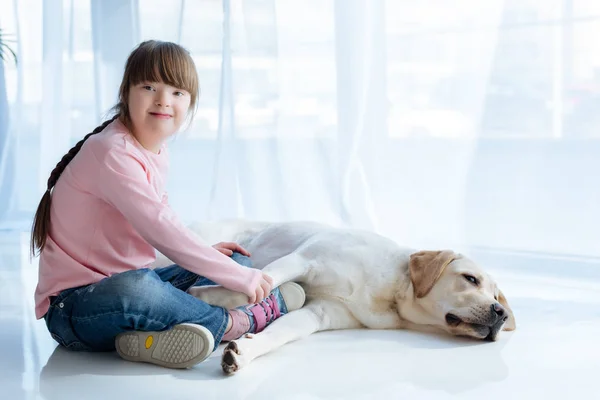 Kid with down syndrome holding Labrador dog paw — Stock Photo